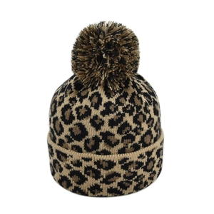 Detailed close-up of leopard print knit winter hat with large faux fur pompom and wide cuff