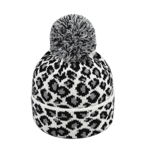 Close-up of winter knit hat with leopard pattern and fluffy tri-color pom-pom detail