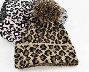 Detailed close-up showing leopard print knit beanies in brown, pink, and grey with pom-poms