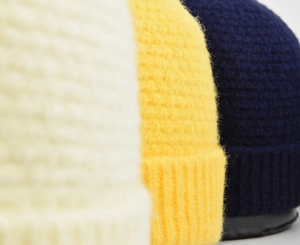 Détail de bonnets en maille gaufre épaisse en jaune, bleu et blanc avec texture côtelée