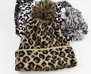Detail of leopard print knit beanies with fluffy pom-poms in various stylish patterns