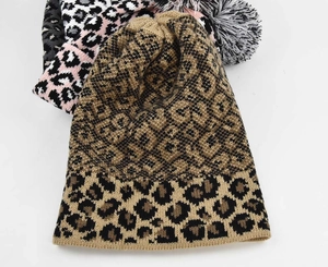Detail of leopard print knitted beanies in various colors with soft pom-pom accents