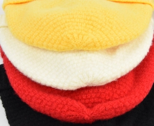 Détail de bonnets d'hiver en maille épaisse en couleurs jaune, beige, rouge et noir