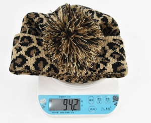 Detail showing a thick leopard print knit beanie weight on a digital scale at 94.2g
