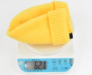 Détail montrant le poids d'un bonnet en maille côtelée jaune vif sur une balance numérique