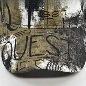 Gros plan d'une casquette camo graffiti avec lettrage QUEST et détails de couture