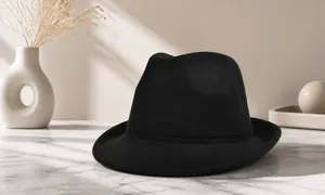 Detail of a vintage black fedora hat with a classic pinched crown and matching ribbon trim