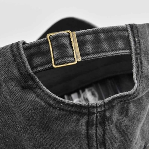Detail of grey washed denim baseball cap with vintage metal buckle and adjustable strap