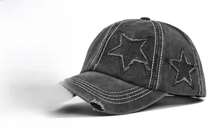 Detail of distressed dark grey washed denim baseball cap with frayed star patch design