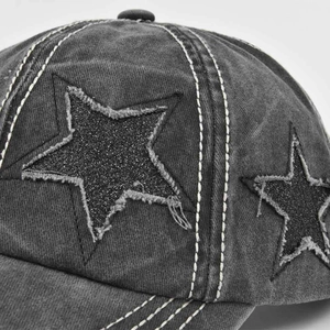 Close-up of distressed grey baseball cap featuring a black glitter star patch and stitching