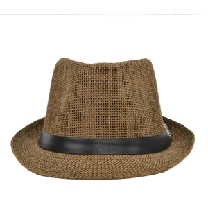Detail of a brown woven straw fedora hat with a black leather band and metal buckle