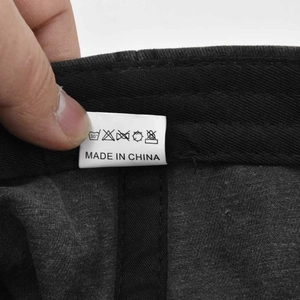 Close-up of a white fabric wash care label on a black washed cotton baseball cap
