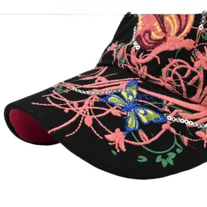Detailed close-up of pink flower and blue butterfly embroidery with sequins on black cap