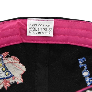 Macro detail of pink sweatband and 100% cotton wash care label inside a black cap