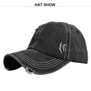Detail of distressed washed black denim baseball cap with embroidery and ripped edges