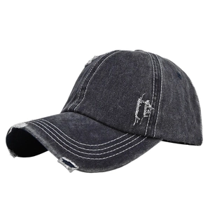 Close-up of distressed vintage grey denim baseball cap with torn details and white stitching