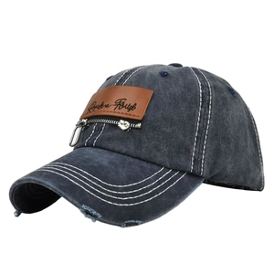 Detail of distressed grey denim baseball cap with leather patch and zipper element