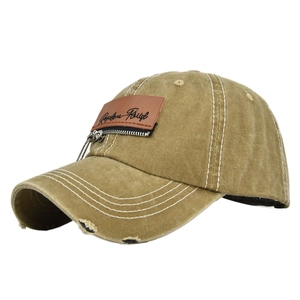 Detail of vintage washed khaki baseball cap with leather patch, zipper, and frayed brim