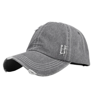 Detailed close-up of distressed charcoal grey denim baseball cap with frayed hole effects