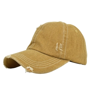 Detailed close-up of distressed ginger denim baseball cap with frayed hole details