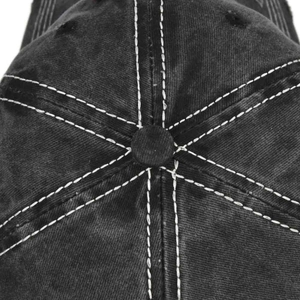 Macro detail of washed cotton baseball cap top showing white stitching and crown button