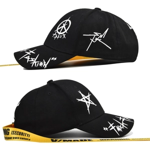 Detail of black baseball cap with white graffiti prints and long yellow security ribbon