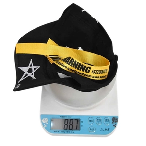 Close-up of black baseball cap featuring star print and yellow industrial warning strap