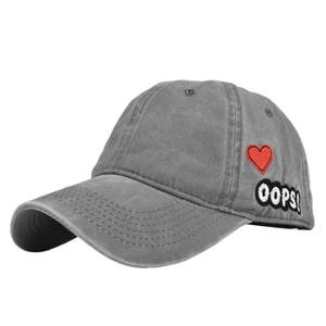 Detailed close-up of heart embroidery and Oops patch on washed grey baseball cap