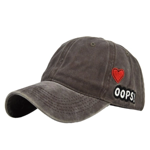 Detail of grey washed cotton baseball cap with red heart and Oops embroidery patch
