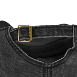 Detail view of washed black denim baseball cap with adjustable bronze metal buckle