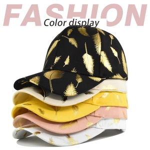 Detail showing five color options of cotton baseball caps with golden feather print