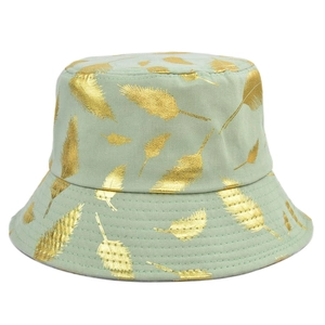 Détail d'un chapeau cloche vert clair avec imprimés feuilles dorées et texture coton