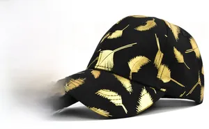 Detailed close-up of metallic gold feather print on a structured black baseball cap fabric