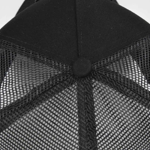 Detailed macro view of black trucker hat showing mesh fabric and top squatchee button