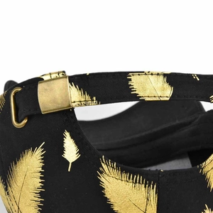 Detailed close-up of golden feather print on black canvas baseball cap with metal buckle