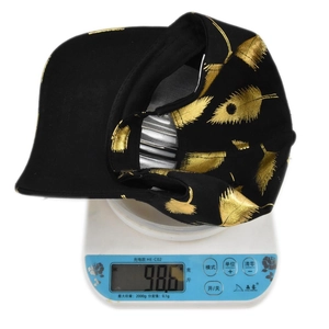 Detailed view of a black baseball cap with gold leaf print weighing only 98.6 grams
