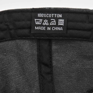 Detailed macro shot of the 100% cotton wash care label inside a black baseball cap