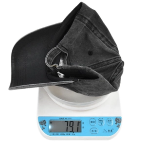 Weight measurement of a distressed black cotton baseball cap showing 79.1g on a scale