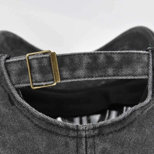 Dettaglio della fibbia in metallo e cuciture sul cappellino in denim lavato