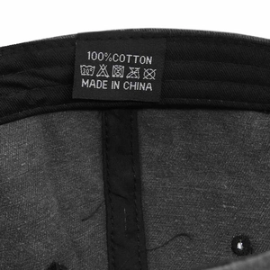 Dettaglio dell'etichetta di lavaggio in 100% cotone e trama del tessuto del cappello baseball