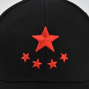 Detailed close-up of red five-star embroidery on a black cotton twill baseball cap