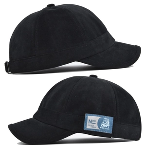 Détail d'une casquette en coton noir à bord court avec étiquette tissée bleue sur le côté