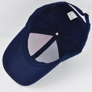 Detail of blue baseball cap interior showing 100% cotton label and rhinestone brim