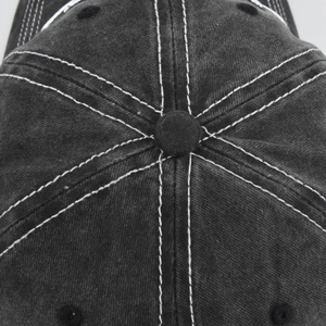 Dettaglio delle cuciture bianche a contrasto e del bottone sulla corona del cappello