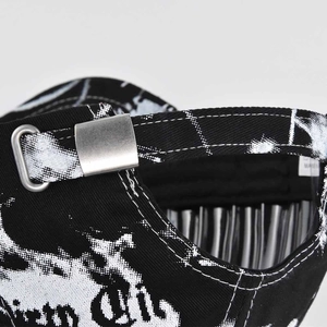 Detail of adjustable metal D-ring buckle on black and white graffiti baseball cap