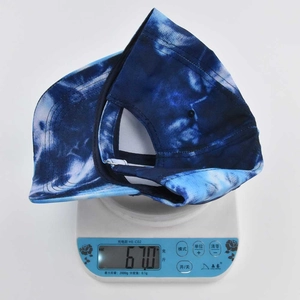 Blue and white tie-dye baseball cap being weighed on a scale showing 67g total weight
