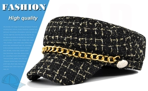 Detail of tweed navy cap with black-gold plaid, chunky gold chain and metal side button