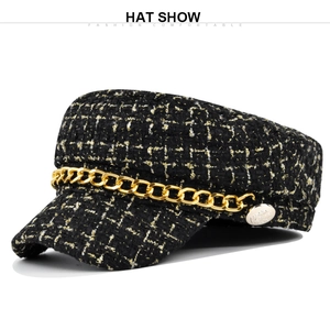 Detail of tweed newsboy hat with gold chain ornament and metallic button accent
