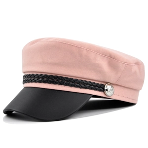 Detail of pink newsboy cap showing woven fabric and black leather brim with metal button