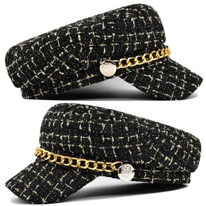 Detail shot of black tweed baker boy hat with golden metal chain and embossed buttons